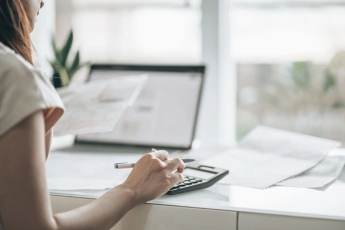 Woman checking online website with pen in hand